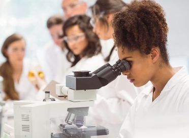 Science student looking through microscope in the lab at the university